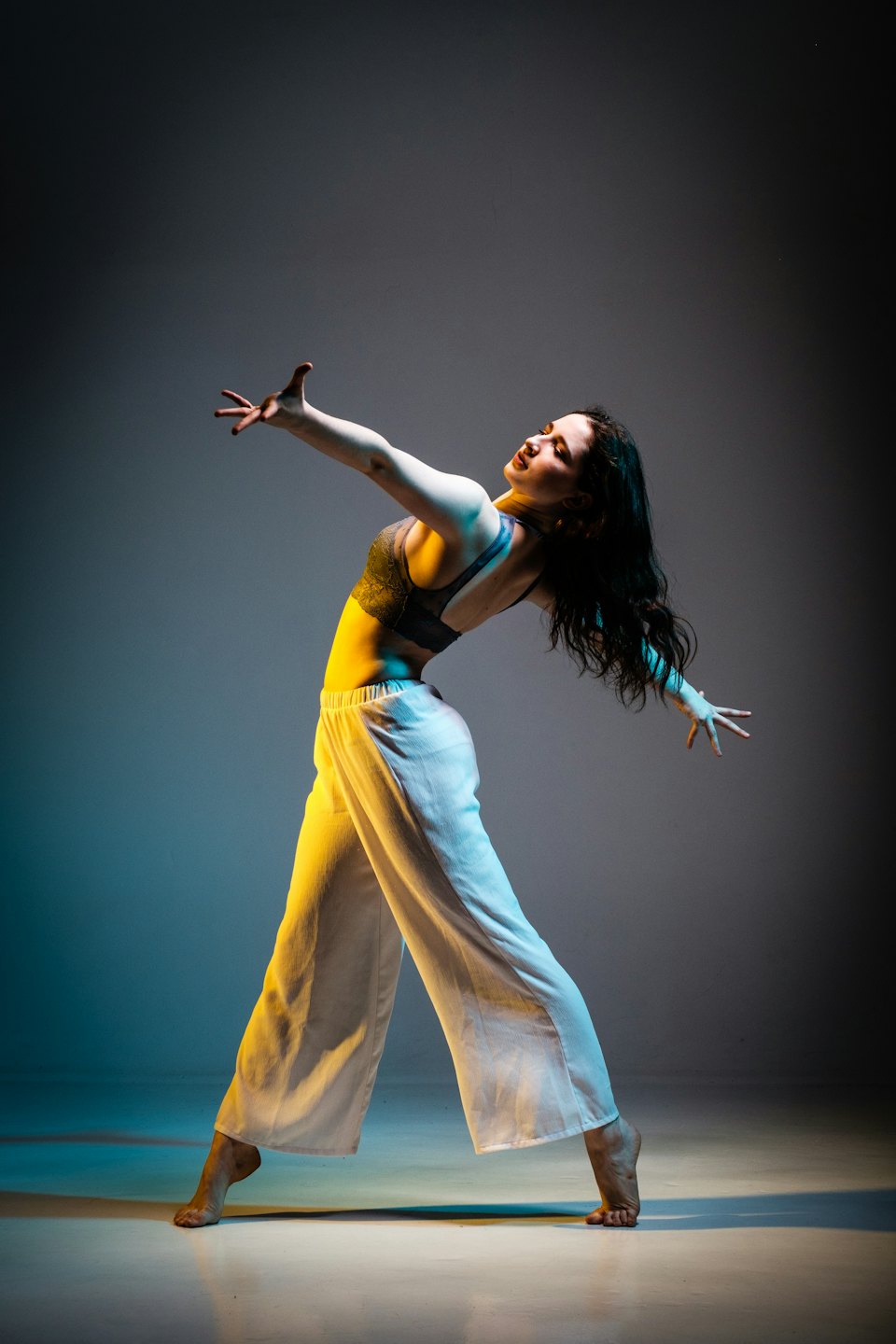 Bailarina en un estudio con los brazos extendidos y la espalda arqueada.