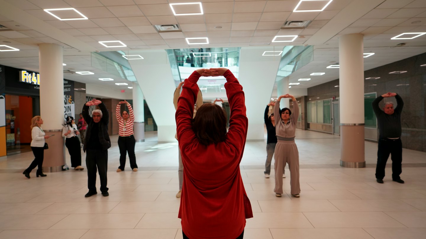 Adultos haciendo estiramientos en un centro comunitario moderno y luminoso.
